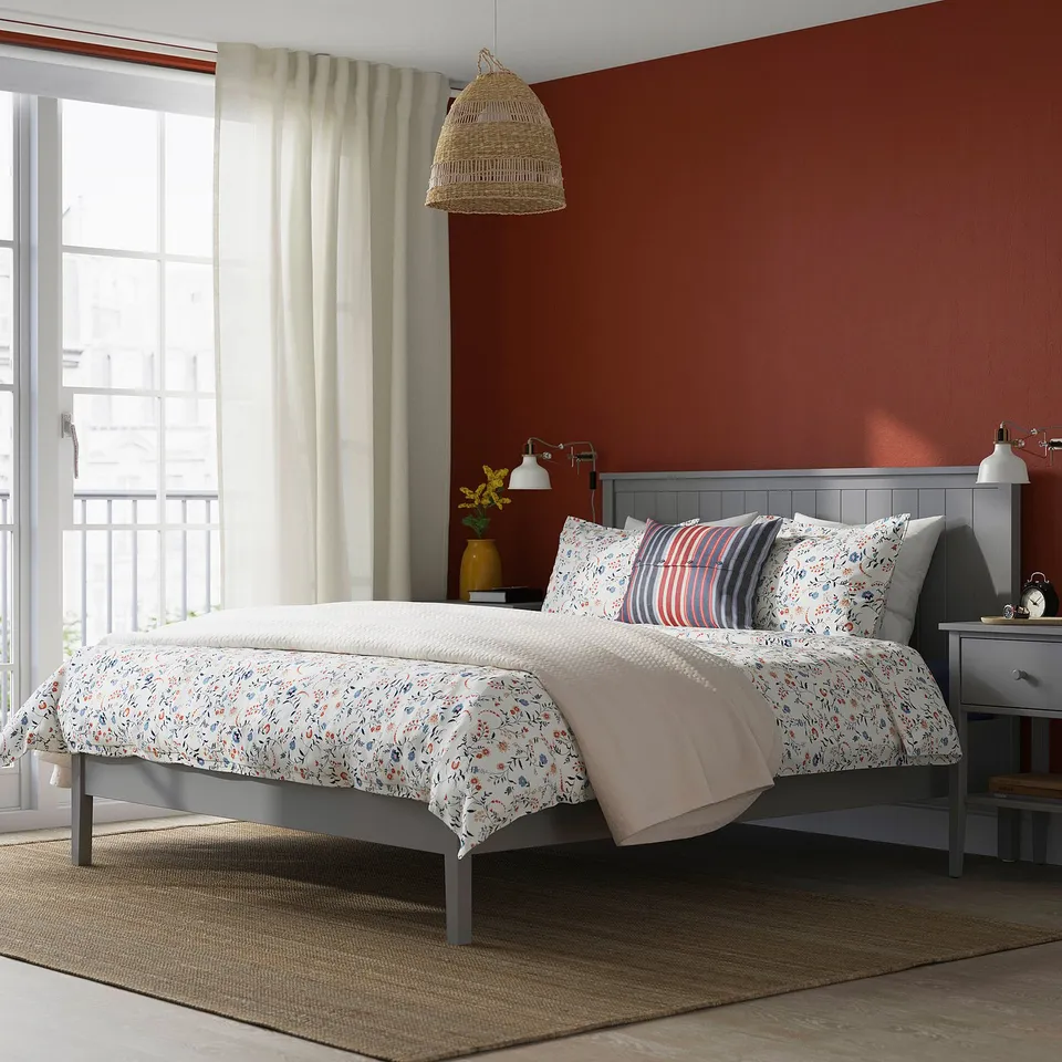 Red bedroom with GULLABERG bed, white curtains, patterned bedding, grey traditional frame.