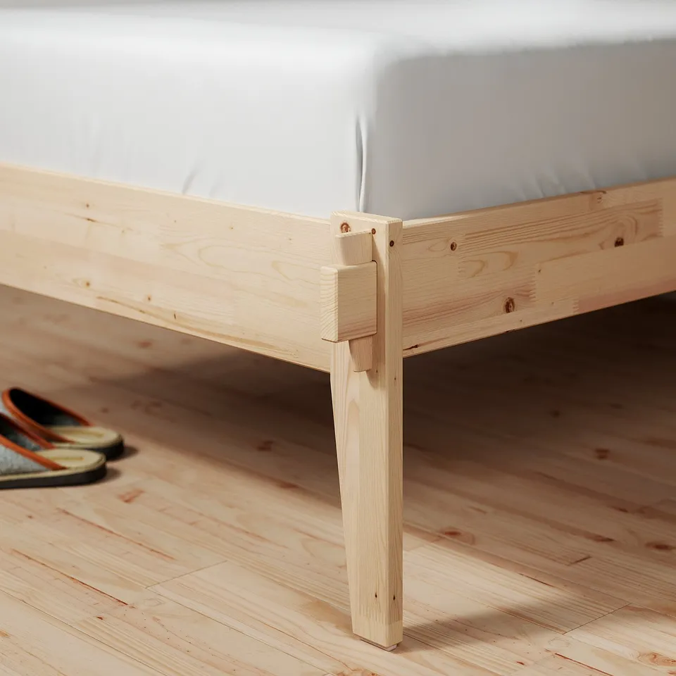 Simple, sturdy wooden bed frame with clean lines. Natural pine finish. Showing corner joint detail and smooth mattress.