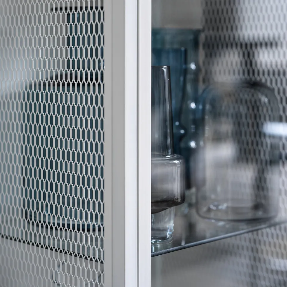 A BAGGEBO glass cabinet with mesh doors in white, displaying glassware inside.
