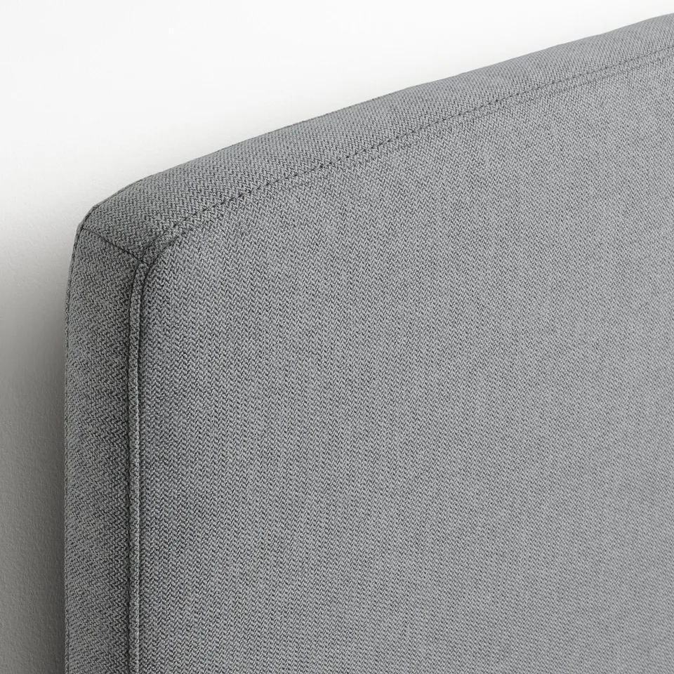 A plush, grey headboard showcasing fine stitching and soft fabric, indicative of quality craftsmanship.