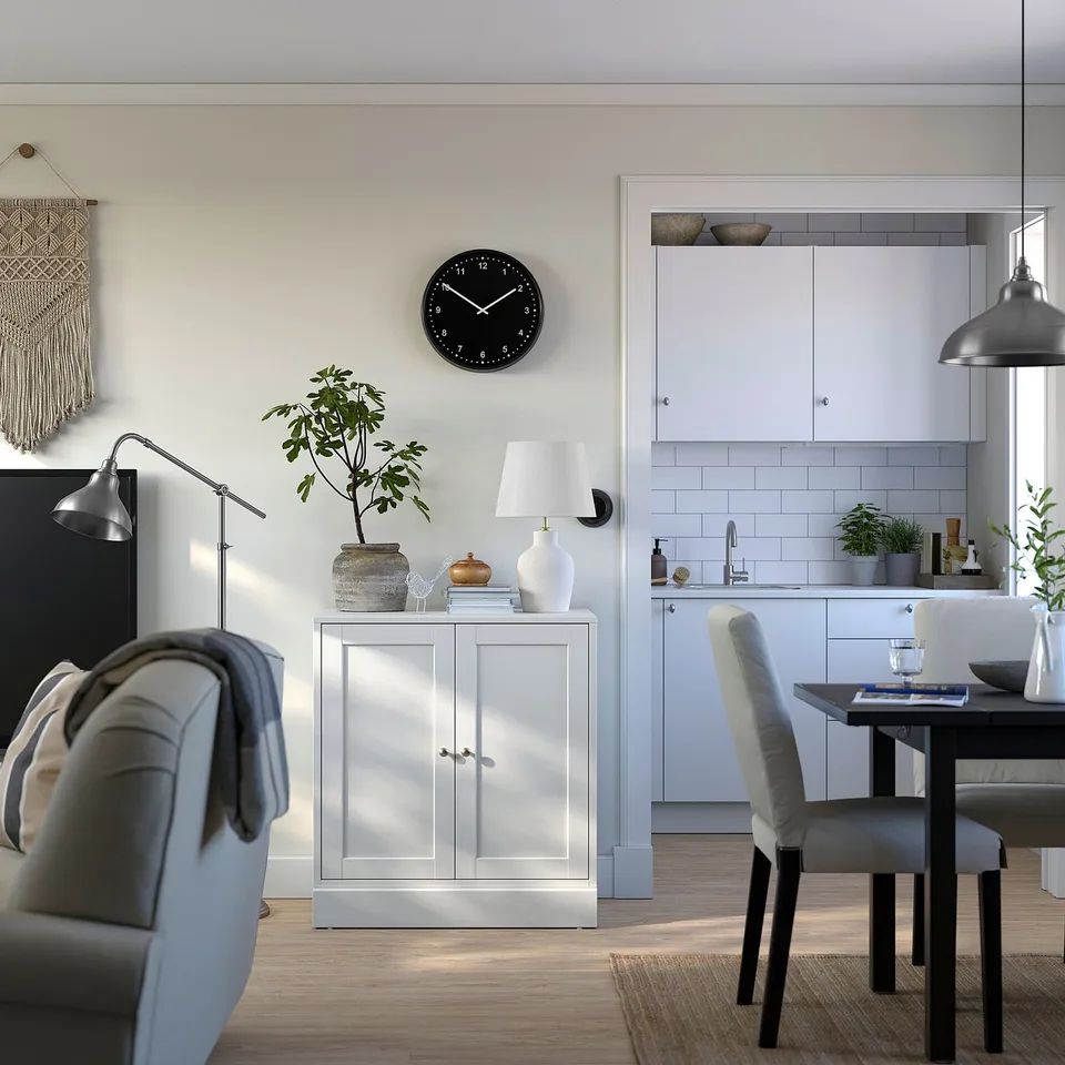 Modern kitchenette with grey HAVSTA cabinet, clock, dining table, plants, and pendant lamps.