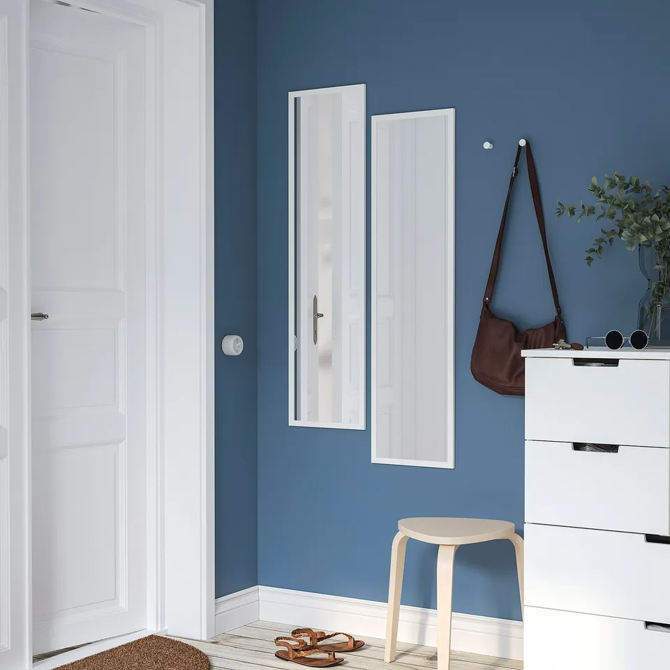 A blue-walled room with a white LILJETRÄD mirror, vertically placed. Its large enough to check outfits, yet fits in tight spaces.