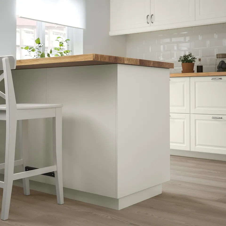 Modern white FÖRBÄTTRA kitchen island with wooden countertop, smaller than surrounding cabinets, and a white stool beside it.