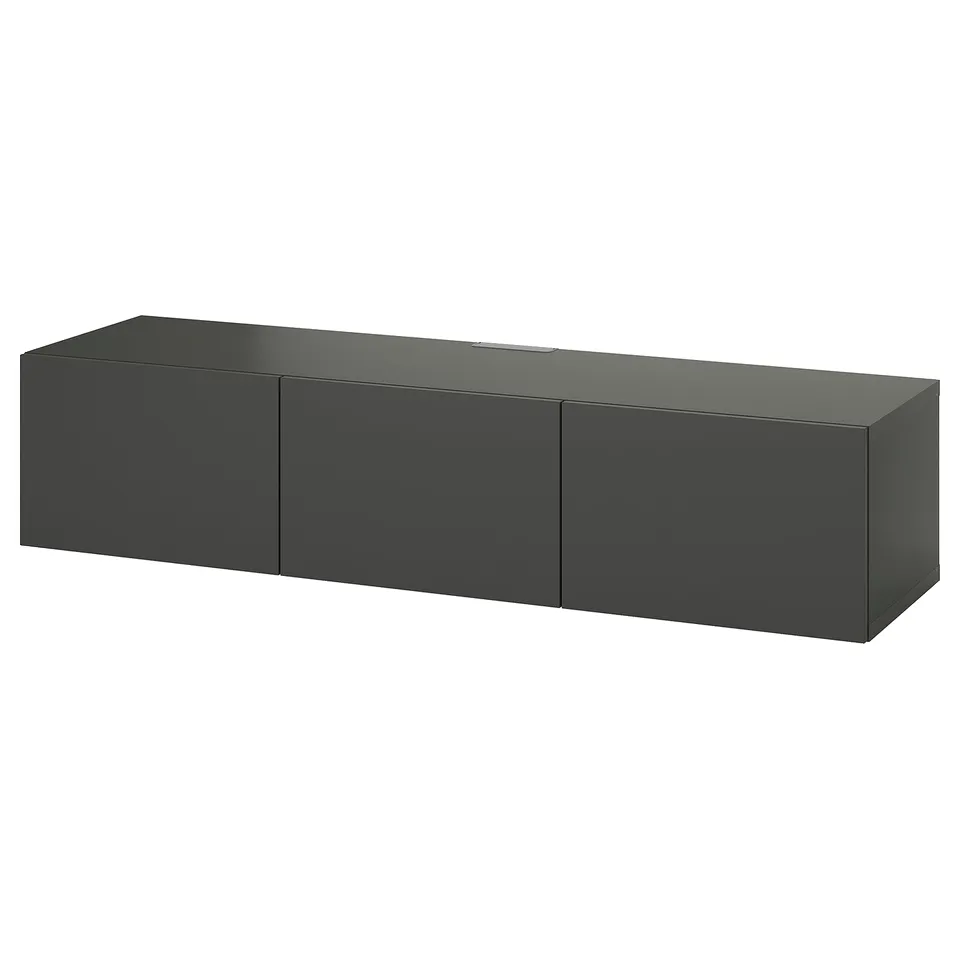 Depicts a minimalist, dark grey BESTÅ tv bench with three closed cabinets. Its wall-mounted for a sleek and airy look.