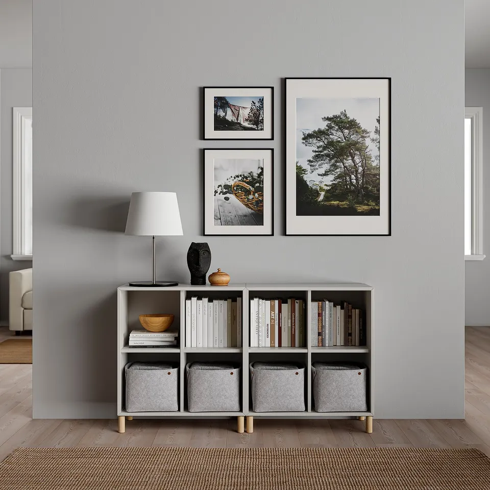 Modern living room setup with white lamp, grey shelves, and black frames on a grey wall.