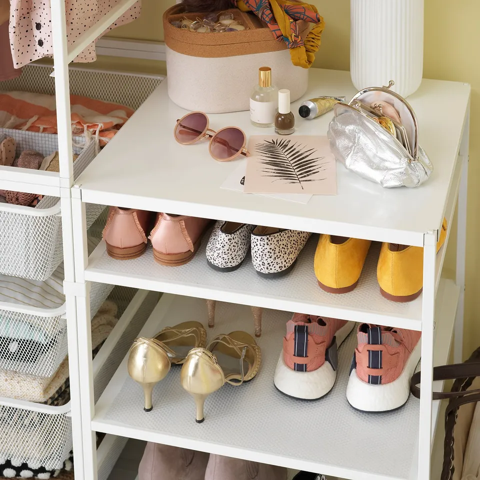 A well-organized white JONAXEL shoe rack, holding colourful shoes, with accessories on top.