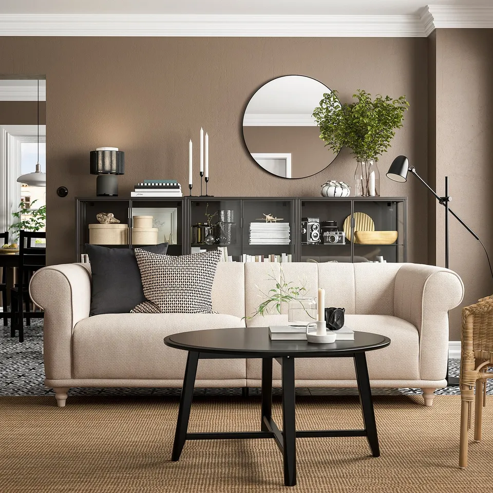Modern living room with beige VISKAFORS sofa, black coffee table, and decor on brown walls.