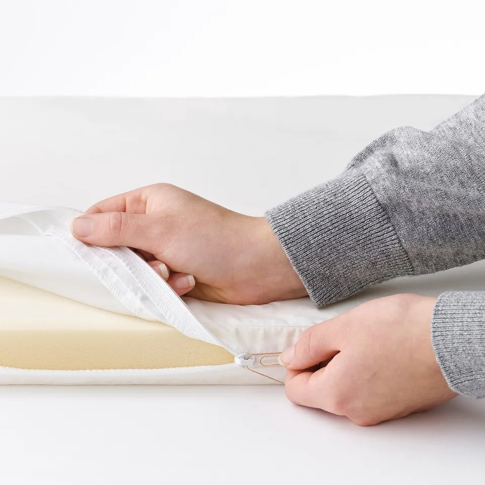 Person placing a white mattress into a bassinet.
