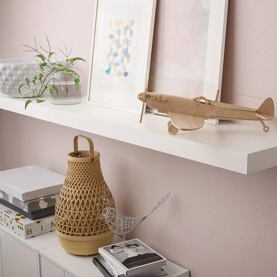 A modern decor a LACK wall shelf, showcasing a wooden aeroplane, baskets, and art, maximising wall space and blending seamlessly into the wall.