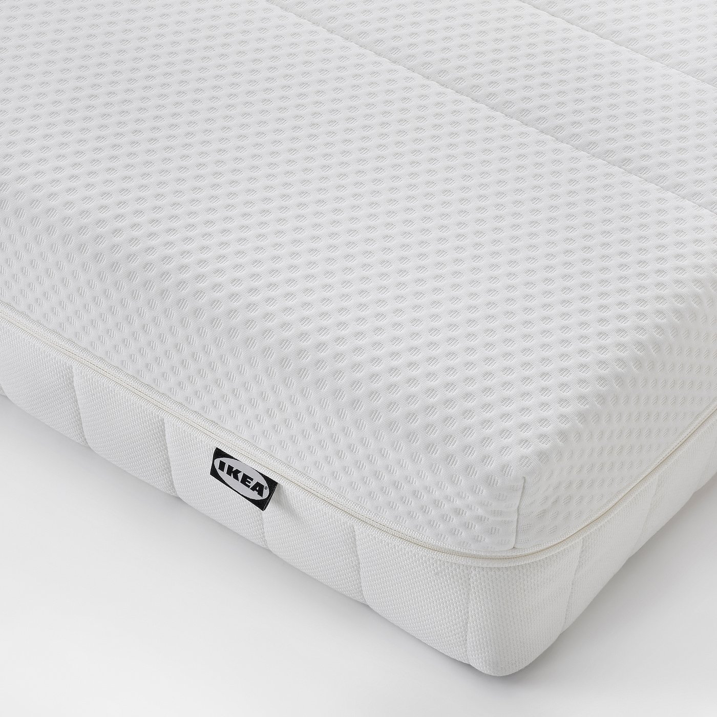 Crisp white foam mattress, neat and well-cushioned, with IKEA label, ensuring comfort and quality.