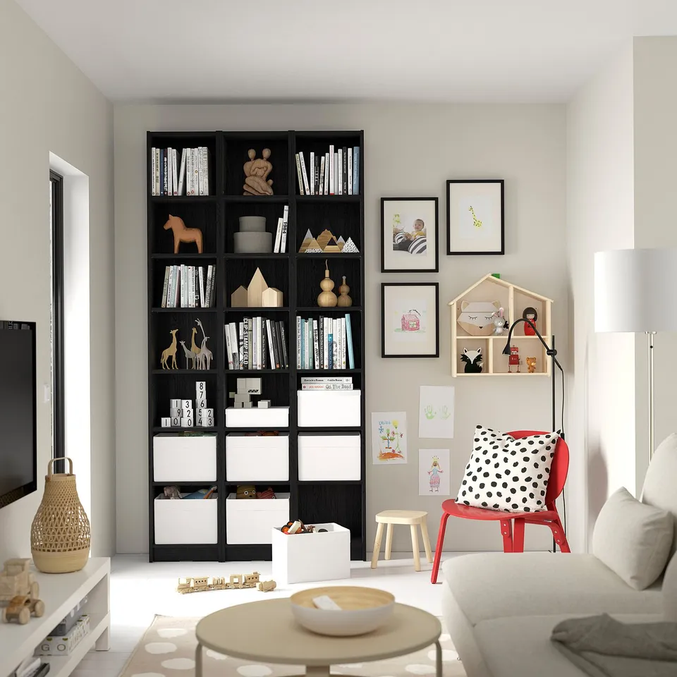 Modern living room with BILLY bookcase filled with books & toys. Cosy family space with red chair & artwork.