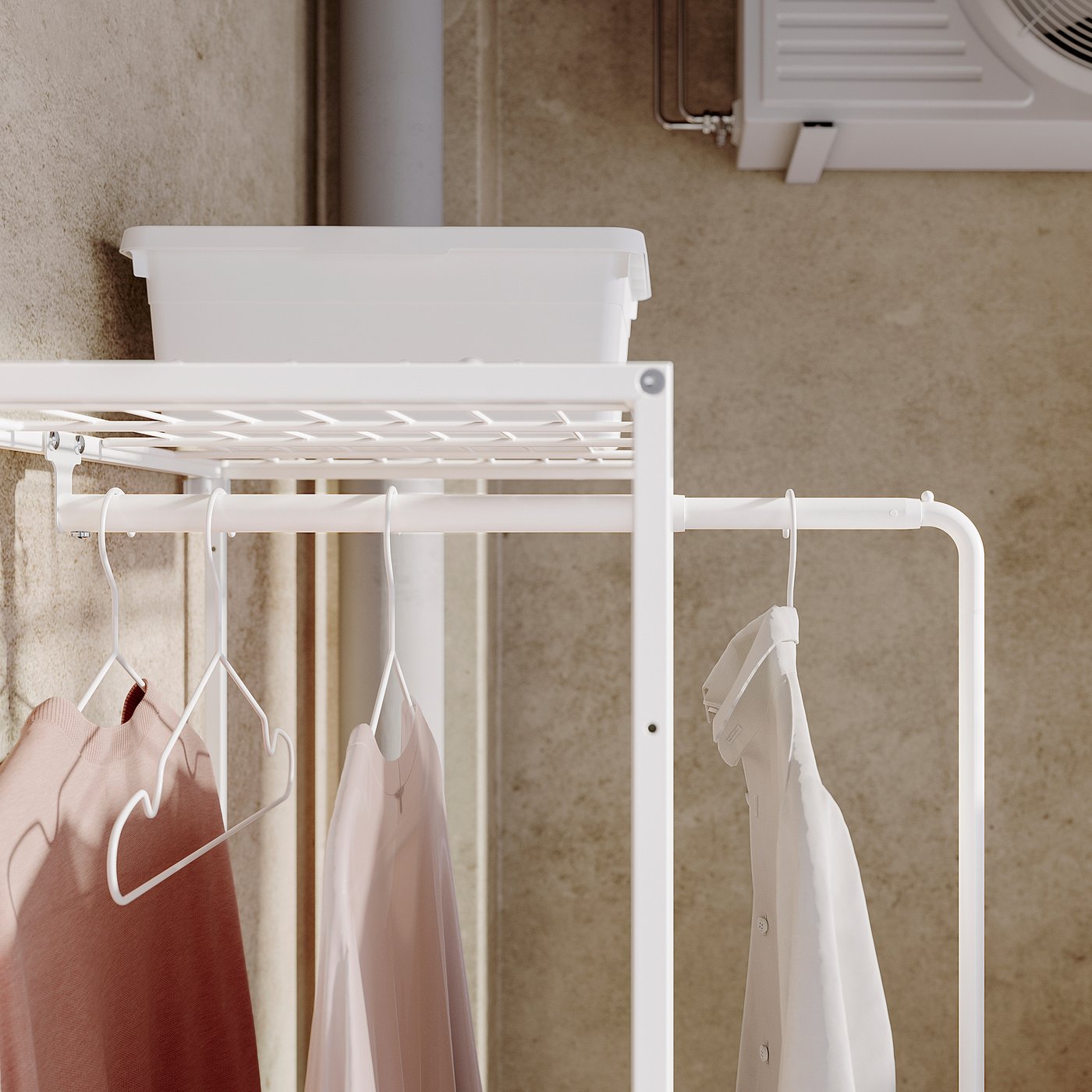 White JOSTEIN hanging clothes rack with shelf holding three hanging garments.