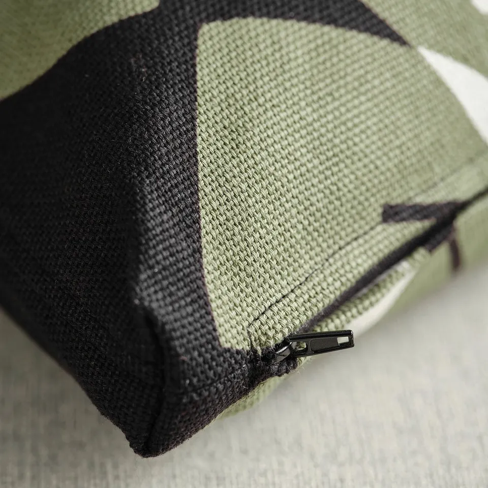 Close-up of durable, green and black cushion with zip, showcasing textured fabric quality.