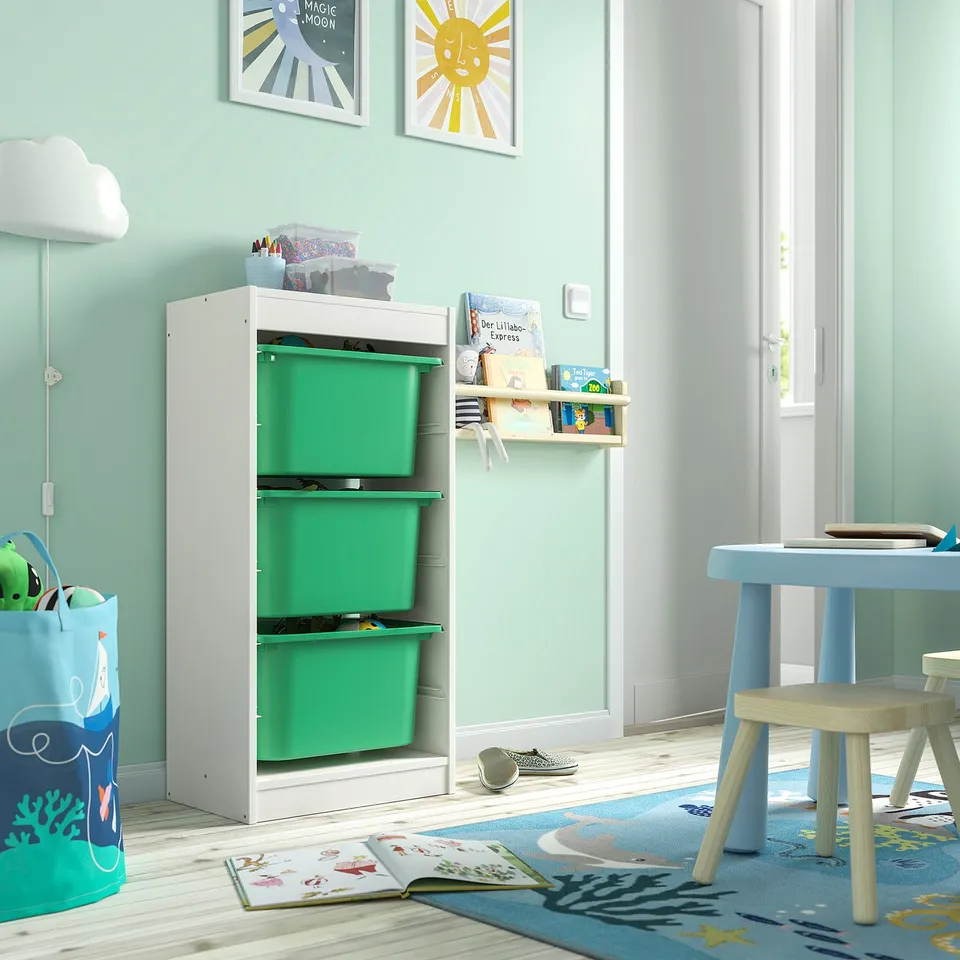 White TROFAST storage with green bins, ideal for toys. Tall, durable, beside blue table.