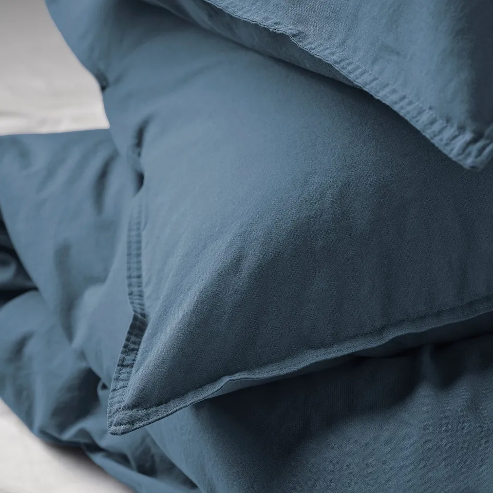 Close-up of soft, blue-gray duvet cover. Pre-washed fabric feels smooth and inviting, ensuring comfort.
