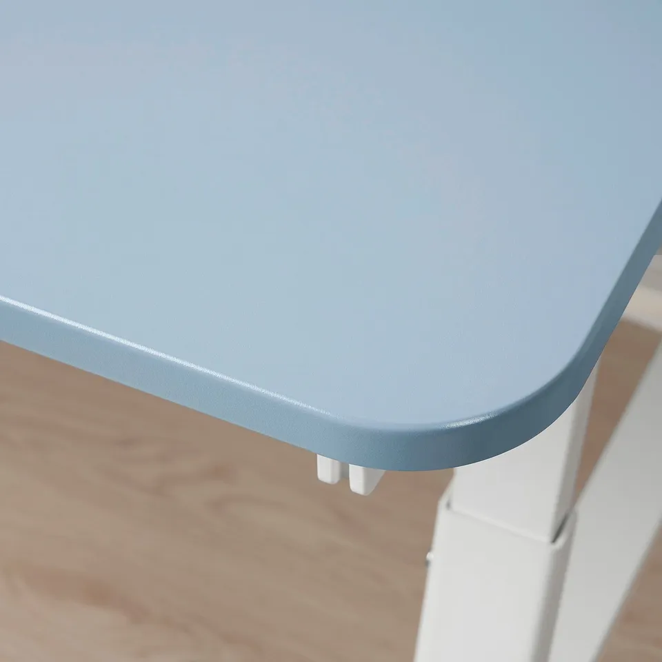 A modern childrens desk shown from above, featuring a smooth, light blue top with white levelling feet.
