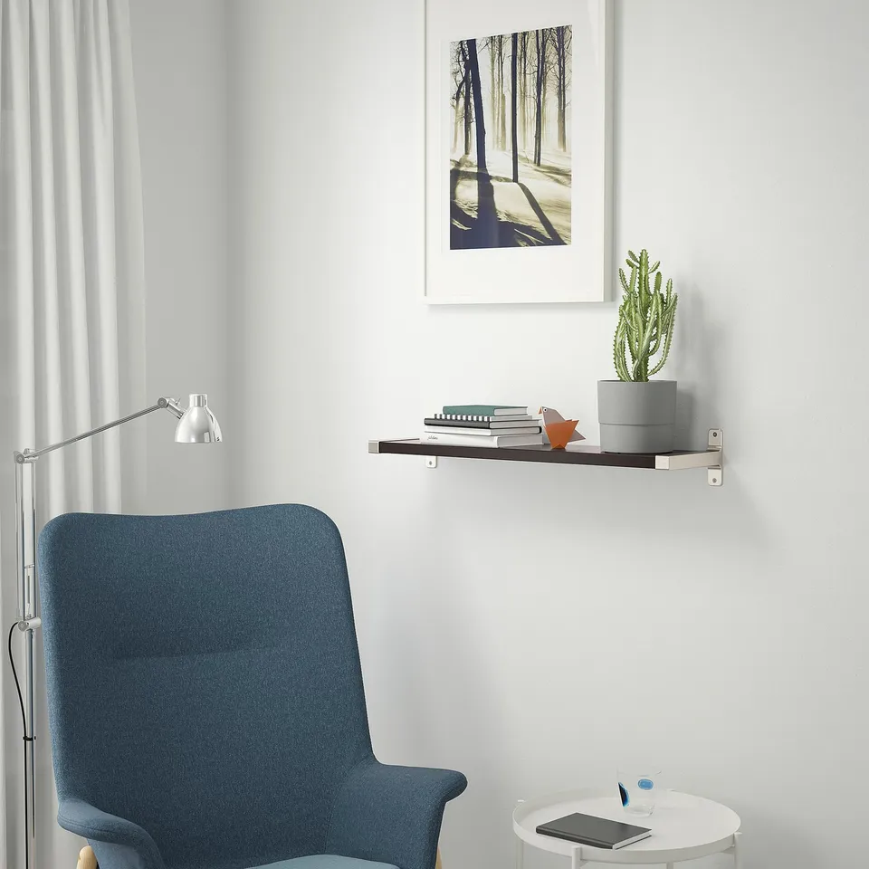Blue armchair, shelf with picture & cactus, reading lamp – cosy corner.