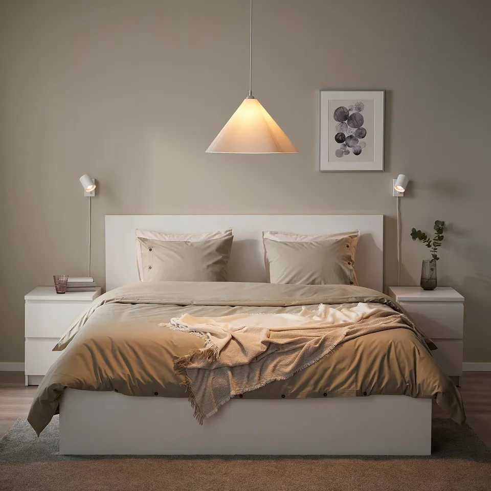 Modern bedroom with ZEBRASÄV lamp over beige bed.