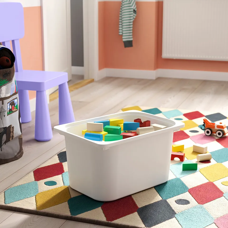 A colourful playroom with wooden blocks in a white TROFAST storage box on a multicoloured rug.