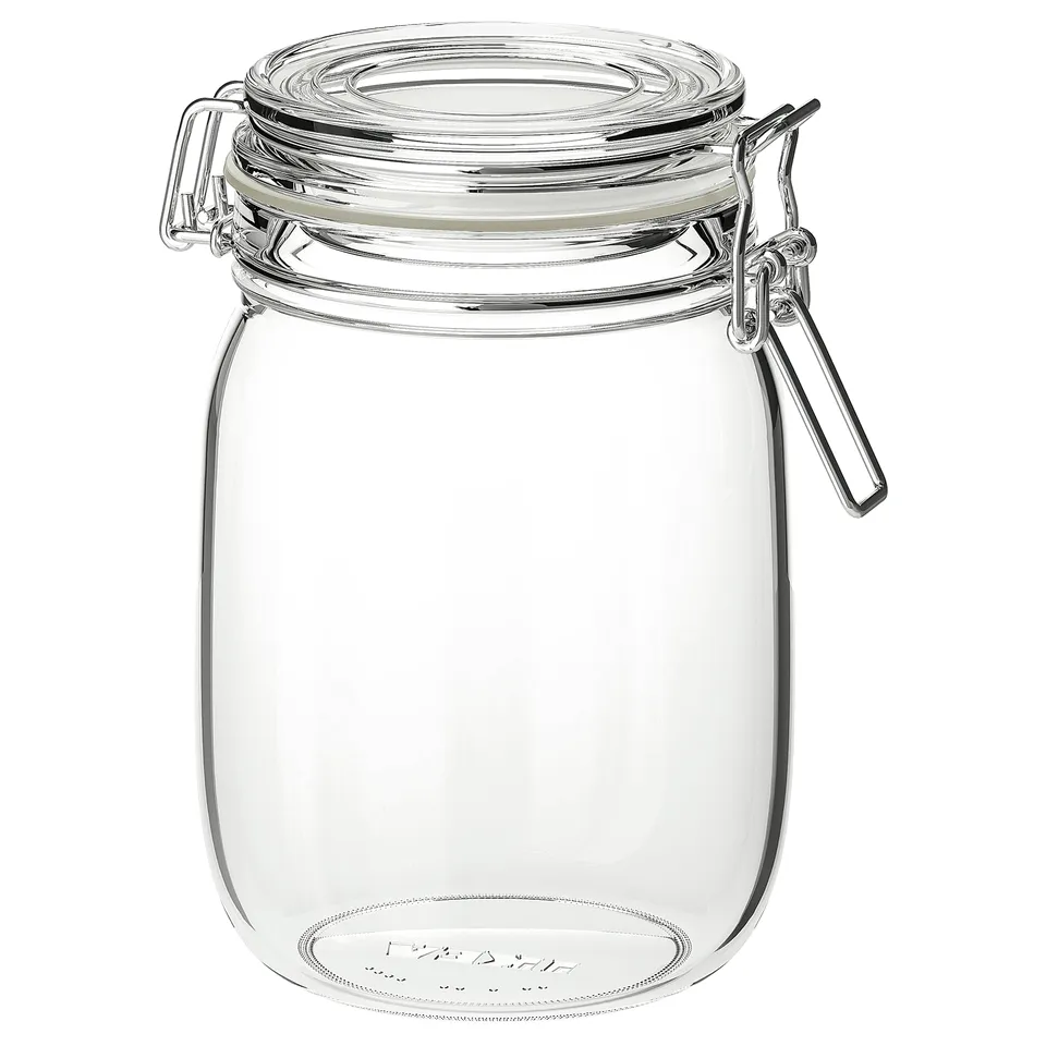 A clear, round glass jar named KORKEN, sealed with a stainless-steel clamped lid. The design is simple and transparent, ideal for kitchen storage.
