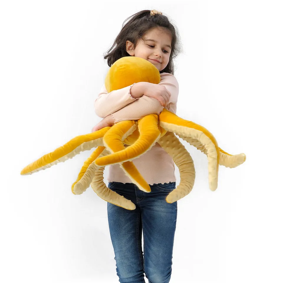 A girl hugs a large yellow plush octopus toy.