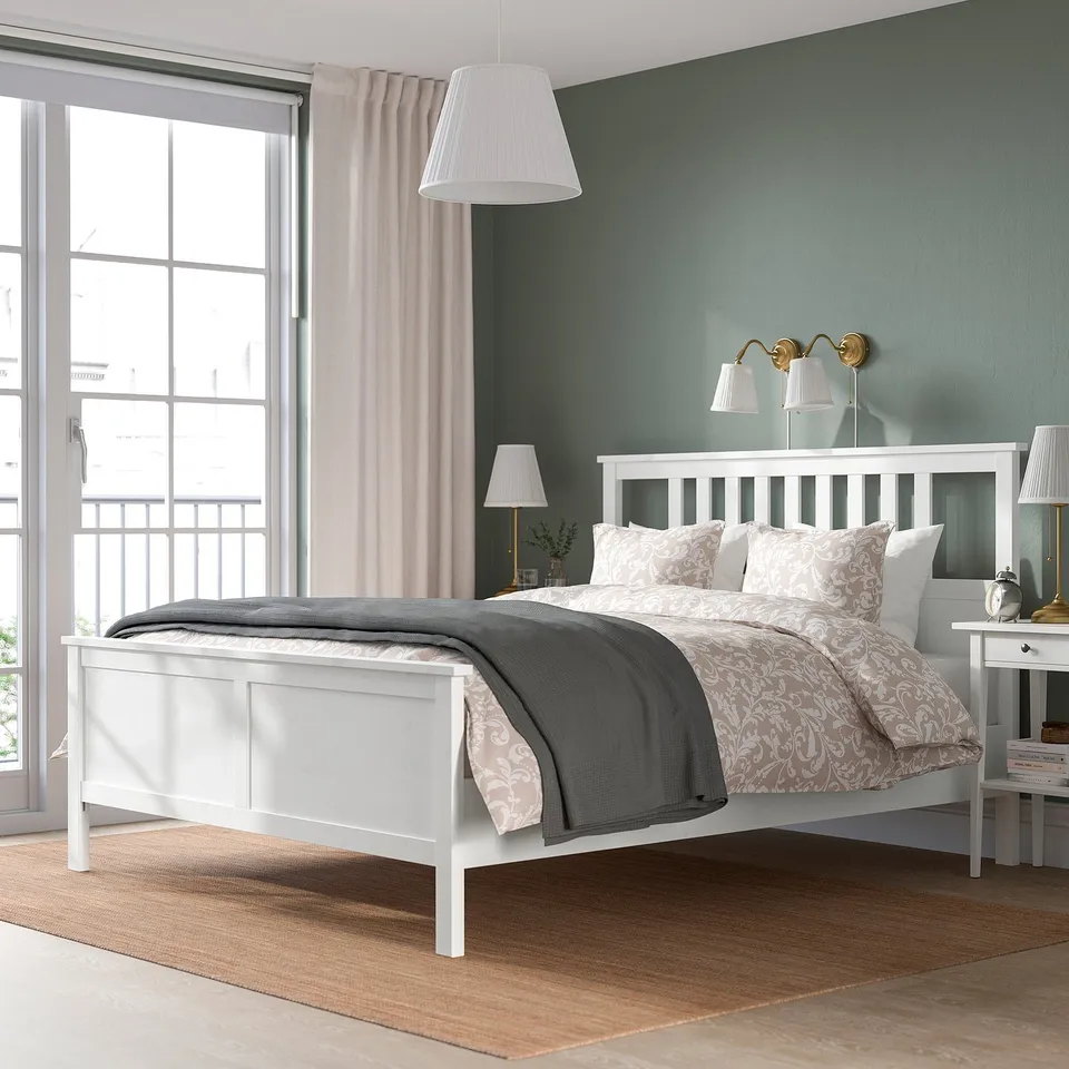 Modern bedroom with HEMNES bed, grey blanket, floral bedding, wall lamps, large window, rug, and nightstands.