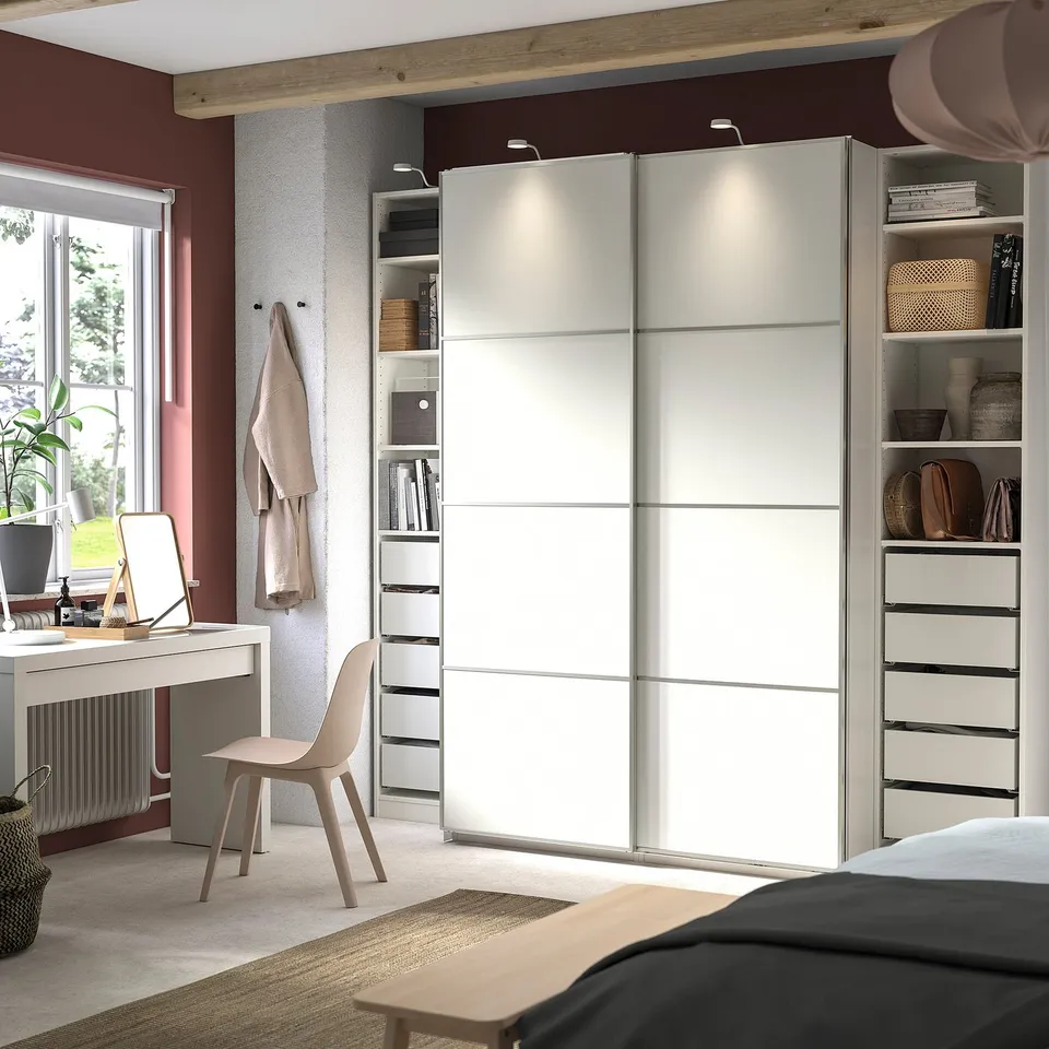 Modern bedroom with white PAX wardrobe, study area, and decor.