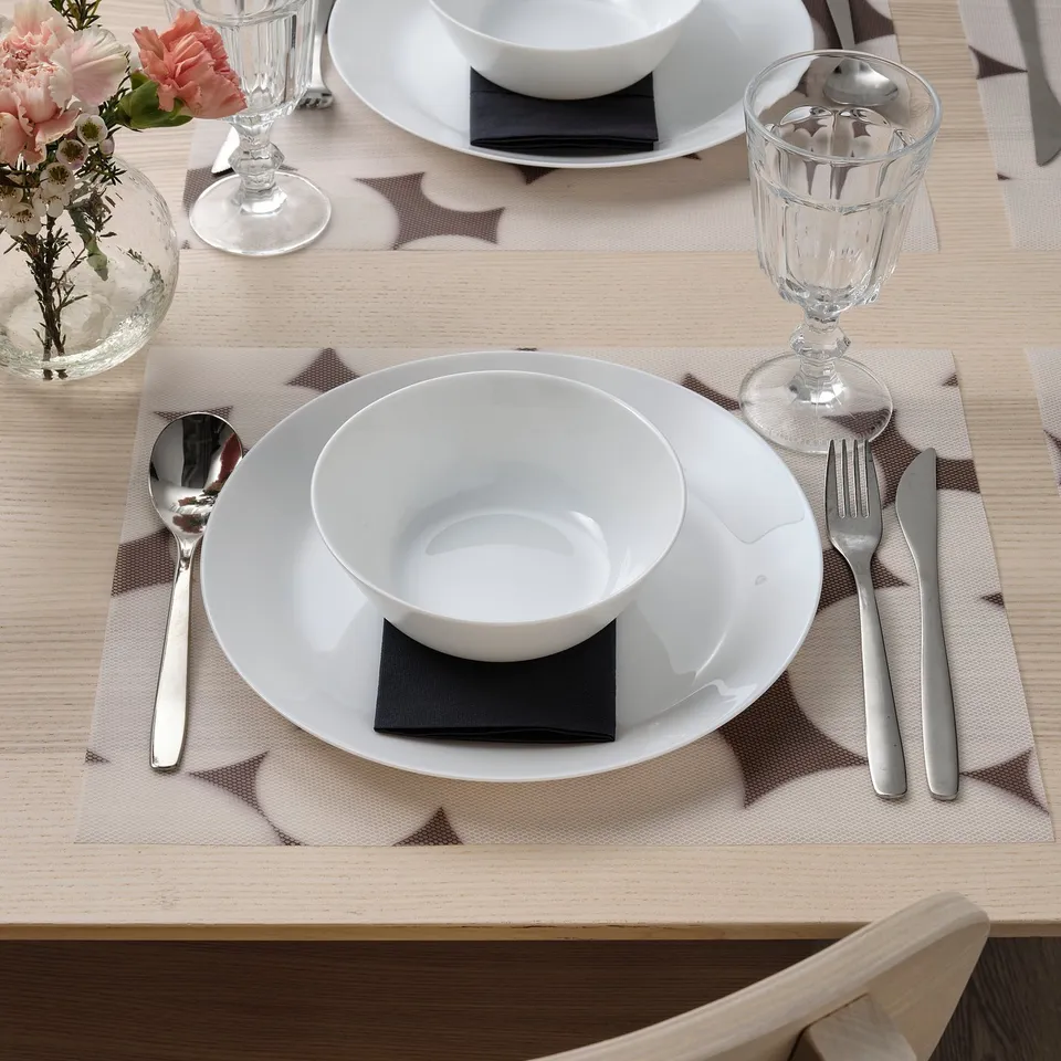 Table setting with VÅRKLYNNE mat, plate, bowl, cutlery, glass, and flowers.