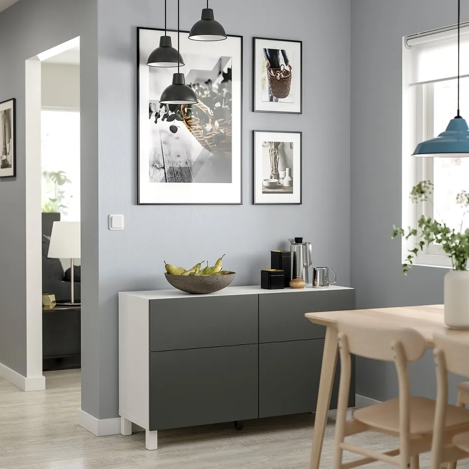 Modern dining area with white and grey BESTÅ storage unit, featuring minimalist art, pendant lights, and natural decor.