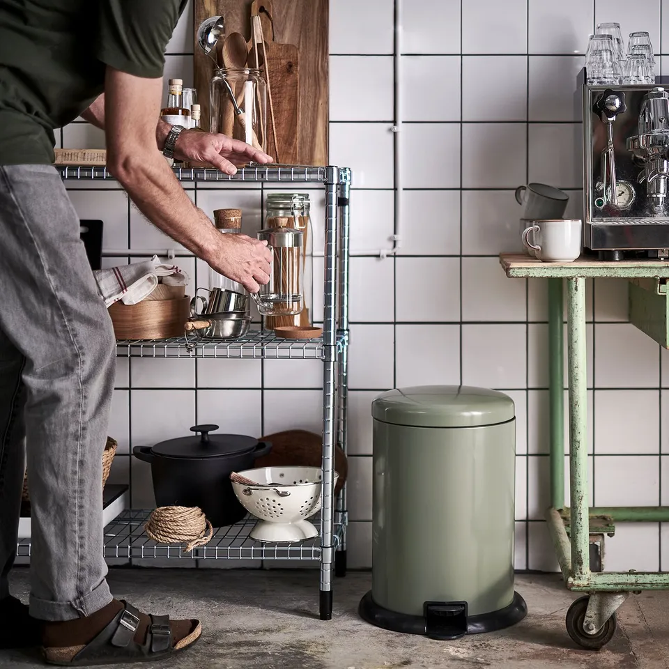 Person reaching for kitchen item on a wire rack.