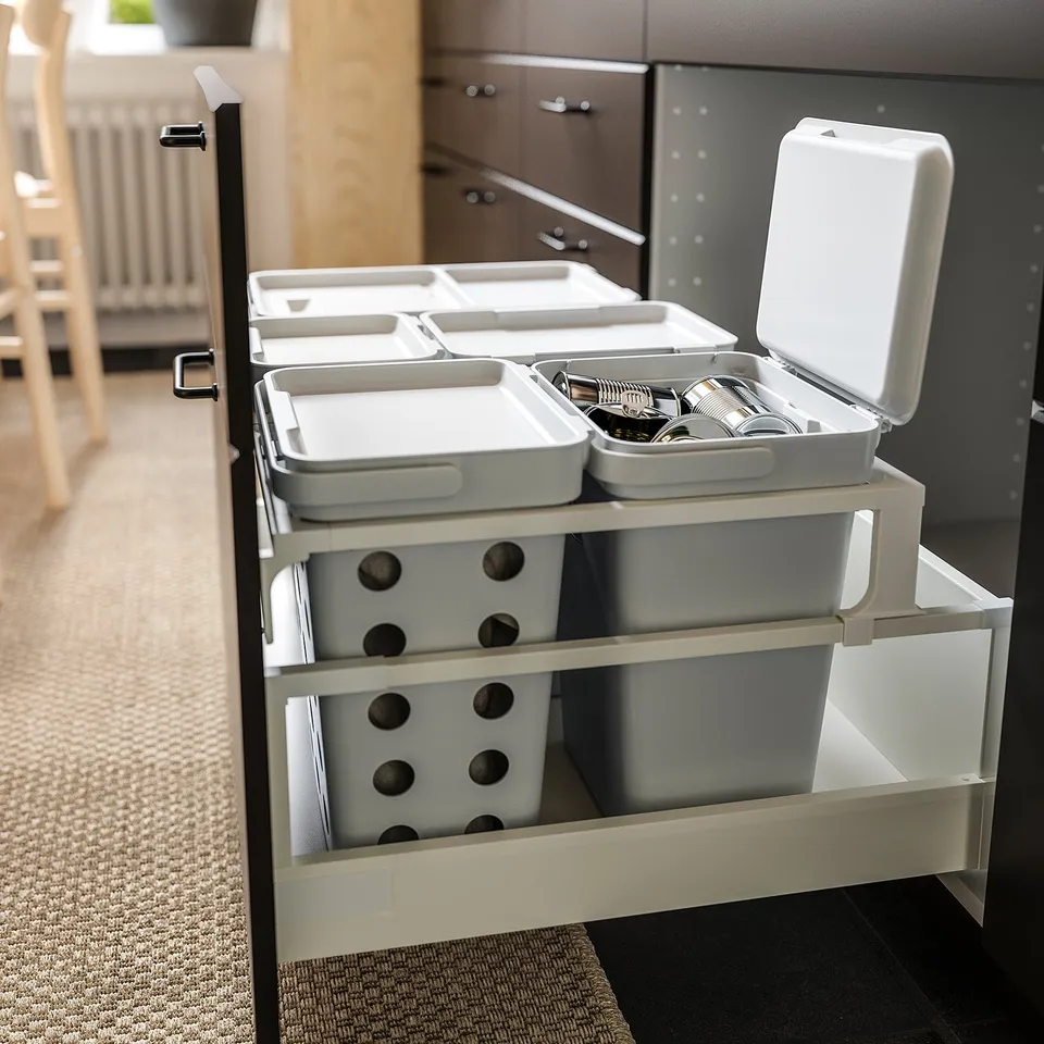 Organised kitchen drawer with multiple white HÅLLBAR waste sorting bins, one open showing cutlery.