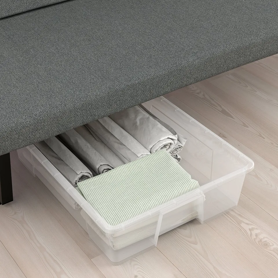 Clear storage bin under bed, holding neatly folded green striped fabric.