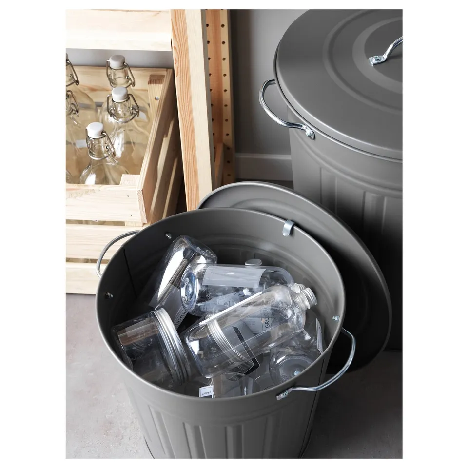 Two round grey bins; one holds plastic bottles, the other is empty. Sturdy handles and lid hook visible.