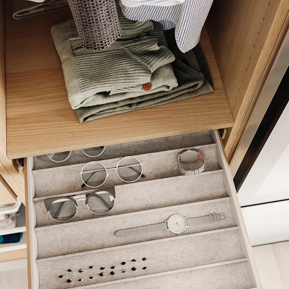 Wooden drawer with grey sweaters and accessories tray.