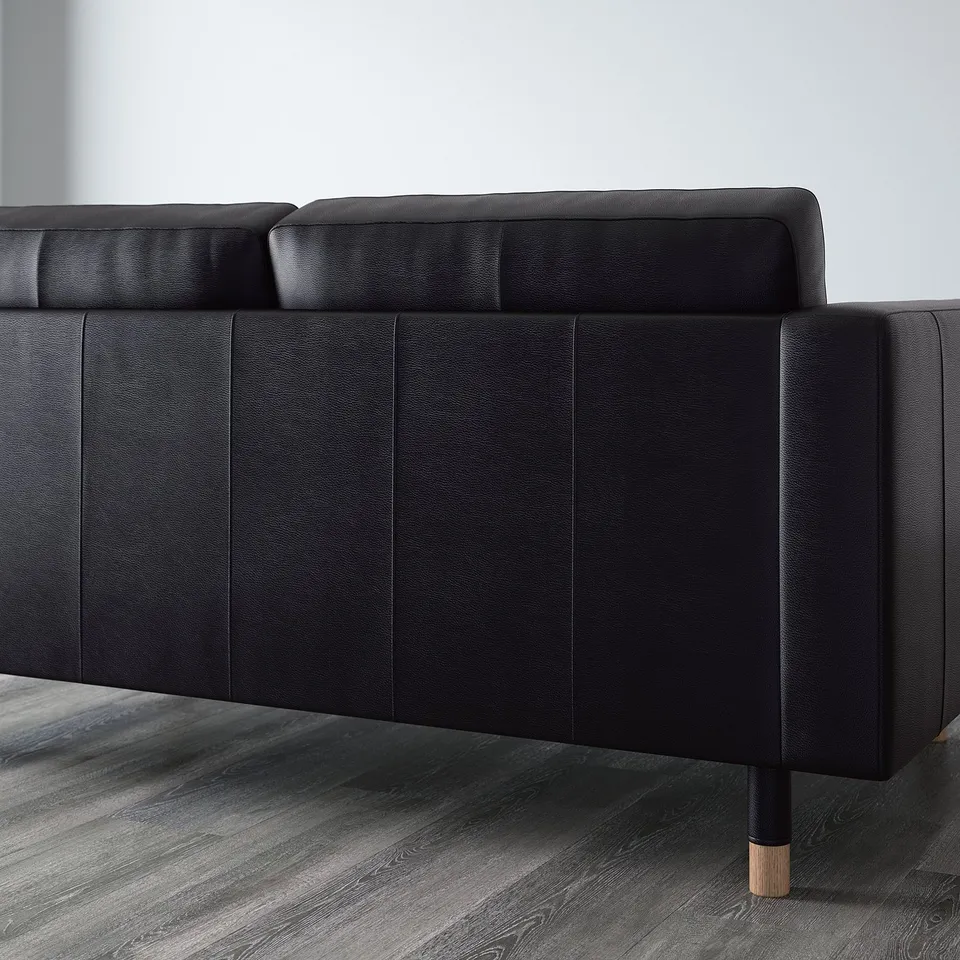 Black leather sofa with cushions, wooden legs. Seating comfort with high-resilience foam and polyester. Removable armrests for adding chaise.