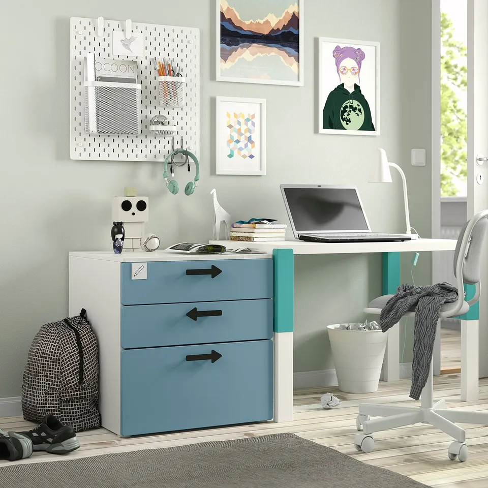 Small kids room with blue-white SMÅSTAD chest & desk, bright decor, and neatly organised study area.