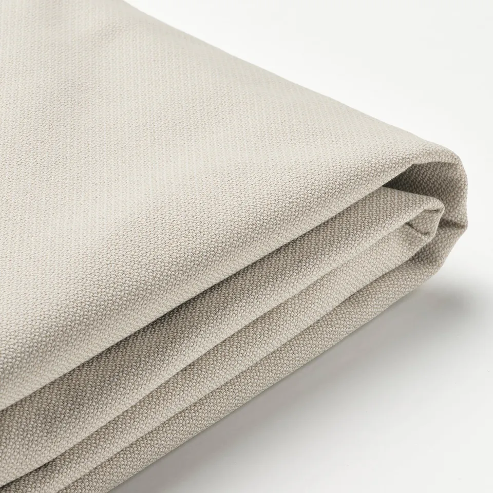 Folded beige fabric bed cover, smooth texture, clean edges.