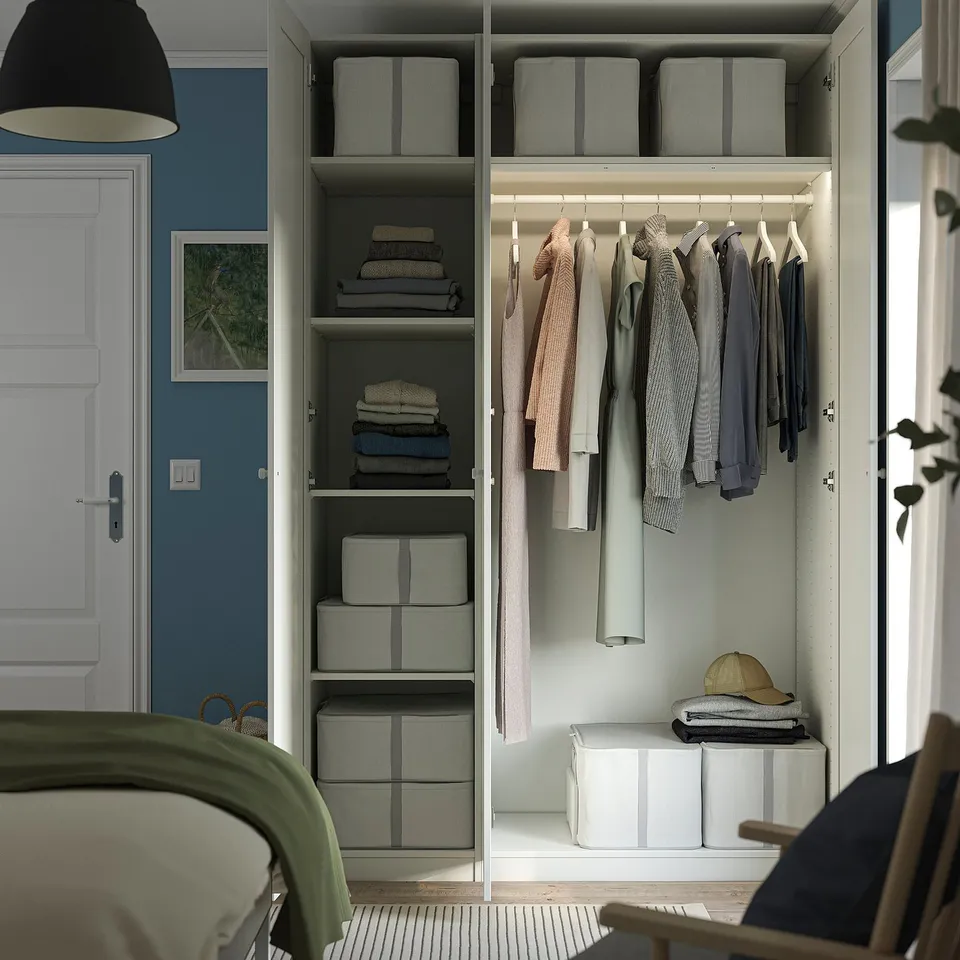 Well-organized closet with shelves, bins, and hanging space. Clothes neatly stored, showing functional storage solutions.