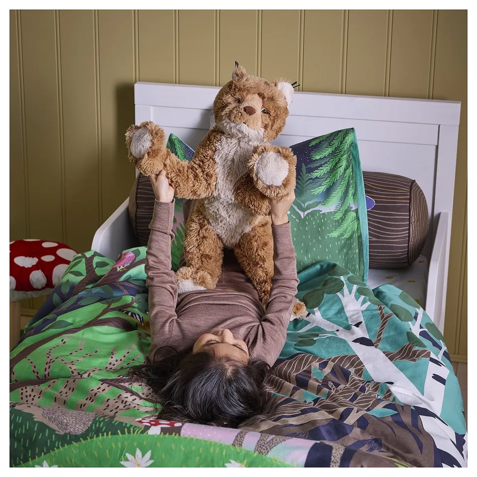 Child with brown lynx toy on green-brown bed