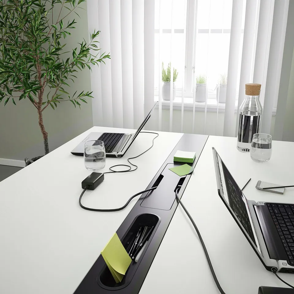 Modern conference table with tech and plants.