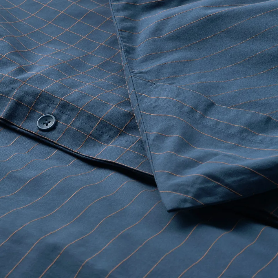 Close-up of duvet cover with chequered pattern, button, and stitching.