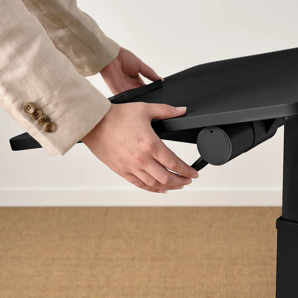 Person adjusting height of mitzzon laptop table, showcasing its gas spring mechanism.