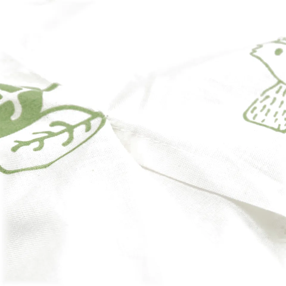 White fabric with green, stylized tree designs, suitable for children aged 3+.