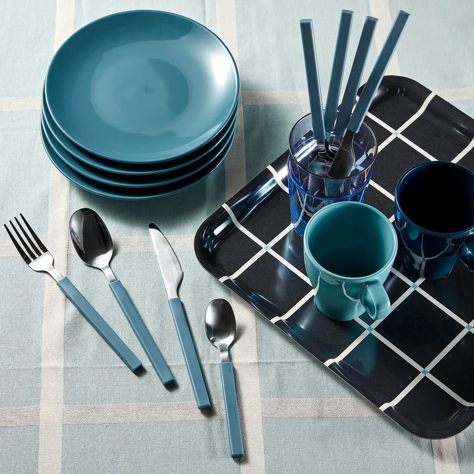 Table setting with teal plates, cups, and utensils. Cutlery includes fork, knife, spoon, and teaspoon, organised on a black and white tray.