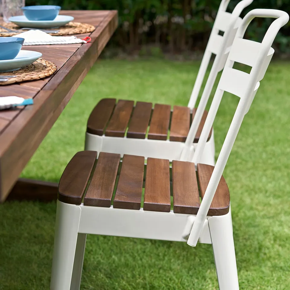 White NORRMANSÖ chair, wooden seat, farmhouse style, outdoors near dining table.