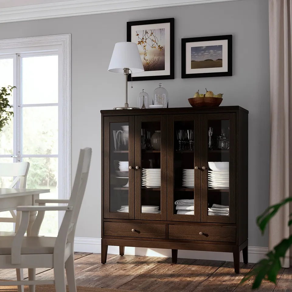 Modern dining room featuring dark wood cabinet with glass doors, white dishes, and framed artwork.