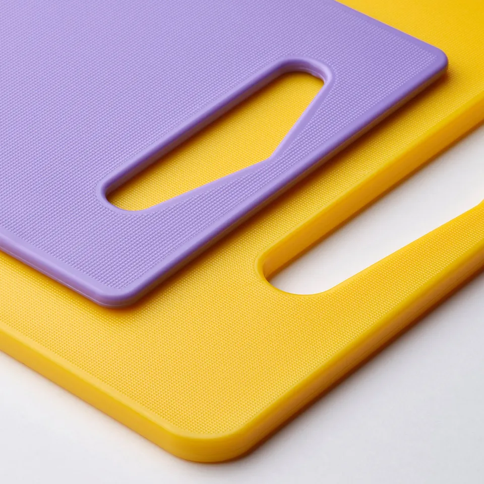 Brightly coloured yellow and purple cutting boards stacked, showing durable plastic handles.