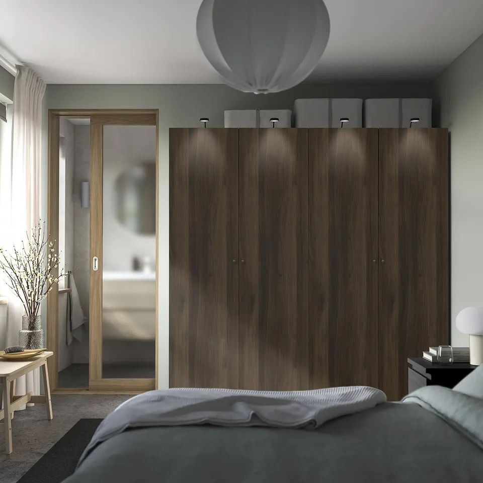 Modern bedroom with dark brown PAX wardrobes and white bedside table. White pendant lamp illuminates the room.