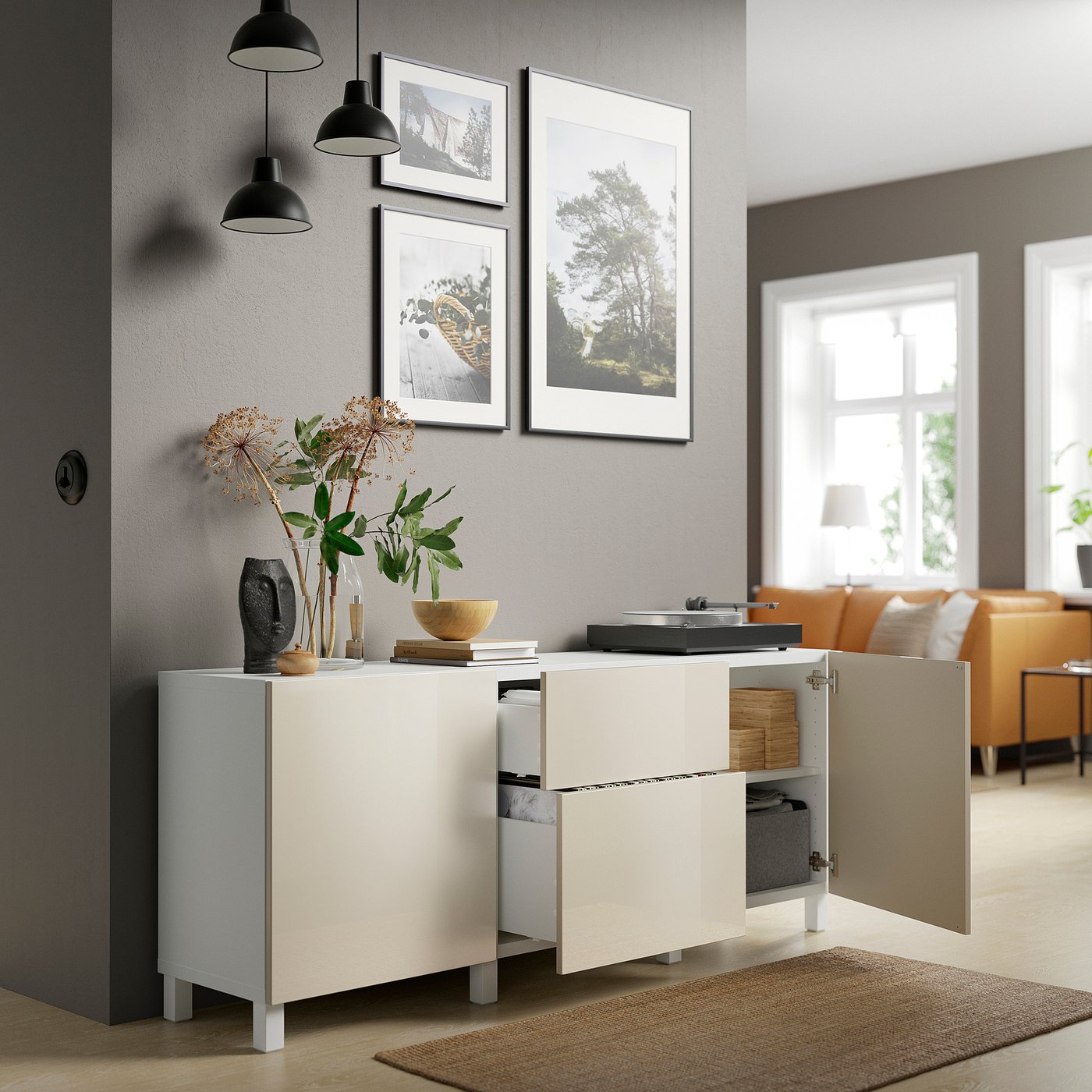 Modern living space with white cabinet, open doors revealing organised storage drawers, styled with plants and decor.