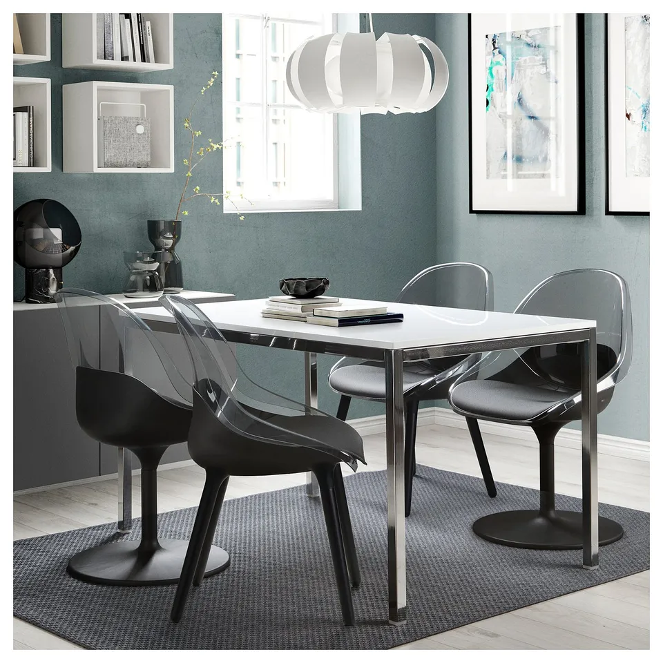Modern dining set with clear plastic chairs and metal table, set against blue wall.